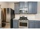 Modern kitchen with stainless steel appliances, gray cabinets, and a gas range at 7481 Absinth Dr, Atlanta, GA 30349