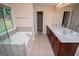 Bathroom featuring double sinks, large mirrors, soaking tub, and a large window at 1015 Buckeye Ln, Villa Rica, GA 30180