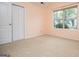 Bright bedroom with large window, neutral carpet, closet, and light peach-painted walls at 1015 Buckeye Ln, Villa Rica, GA 30180