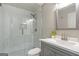 Modern bathroom featuring tiled shower with glass door, vanity with grey cabinets, and large mirror at 8710 Gilmer Ft, Cumming, GA 30028