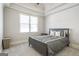 Neutral-toned bedroom with tray ceiling features a bed with striped linens and bright natural light at 8710 Gilmer Ft, Cumming, GA 30028