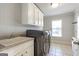 Well-lit laundry room boasts modern washer and dryer, white cabinetry, and a utility sink at 8710 Gilmer Ft, Cumming, GA 30028