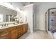 Beautiful main bathroom with double sinks, wood cabinetry, and a tiled shower at 8710 Gilmer Ft, Cumming, GA 30028