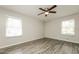 Bright bedroom with two windows, ceiling fan, and modern gray wood-look flooring at 543 Tahoe Cir, Stone Mountain, GA 30083