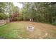 Large backyard with a fire pit, play swing set, and shed surrounded by mature trees at 95 Blue Grass Ct, Oxford, GA 30054