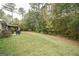 Large backyard with a patio, grill, seating area, mature trees, and ample green space at 95 Blue Grass Ct, Oxford, GA 30054