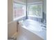 Bright bathroom features a soaking tub beneath dual windows, offering a relaxing space at 95 Blue Grass Ct, Oxford, GA 30054