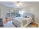 Bright bedroom featuring hardwood floors, an upholstered bed, three large windows, and a ceiling fan at 1017 Preserve Park Dr, Loganville, GA 30052