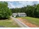 Beautiful home featuring a long driveway and lush green lawn surrounded by trees at 138 Sam Solomon Rd, Locust Grove, GA 30248