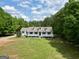 Charming home featuring a covered porch and pristine lawn surrounded by lush greenery at 138 Sam Solomon Rd, Locust Grove, GA 30248