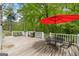 Back deck featuring a grill, dining table with a red umbrella, and mature shade trees at 614 Highway 85 Conn, Brooks, GA 30205