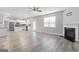 Open concept living room with fireplace, ceiling fan, and kitchen area featuring wood-look flooring at 8069 Louis Dr, Locust Grove, GA 30248