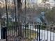 Elegant home viewed from behind a decorative iron gate surrounded by mature trees and lush greenery at 145 E Lake Dr, Mountain Park, GA 30075