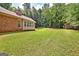 Large backyard featuring a brick home with neutral trim, green grass, and a wooded treeline at 250 Kari Glen Dr, Fayetteville, GA 30215