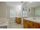 Double vanity bathroom featuring a tile floor, neutral walls, soaking tub, and a window at 250 Kari Glen Dr, Fayetteville, GA 30215