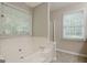 Neutral bathroom showcasing a soaking tub with tile surround, neutral walls, tile floor, and two windows at 250 Kari Glen Dr, Fayetteville, GA 30215