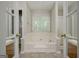 Spa-like bathroom showcasing a soaking tub with tile surround, neutral walls, tile floor, and windows at 250 Kari Glen Dr, Fayetteville, GA 30215