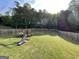 Well-maintained back yard with lush grass, wooden fence, play set and trees at 4092 River Mist Ct, Lithonia, GA 30038