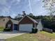 View of the side of the home showcasing a two-car garage and wooded surroundings at 4092 River Mist Ct, Lithonia, GA 30038