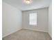 A simple, carpeted bedroom with a single window and neutral paint, illuminated by a ceiling light at 8714 Lakeview Commons # 48, Jonesboro, GA 30238