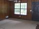Cozy living room with classic wood paneling, large window, and neutral carpeting at 7225 Pineneedle Sw Dr, Covington, GA 30014
