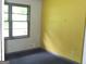 A bedroom featuring yellow accent wall, natural light, and dark carpeting at 9176 Carr Sw Cir, Covington, GA 30014