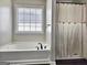 Bathroom featuring a soaking tub, shower with curtain, and large window at 247 Water Oak Ln, Jonesboro, GA 30238