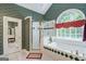 Bright bathroom featuring a soaking tub, tiled shower, and unique arched window at 3644 Graycliff Rd, Snellville, GA 30039