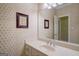 Well-lit bathroom featuring a vanity with sink, mirror, and patterned wallpaper at 3644 Graycliff Rd, Snellville, GA 30039