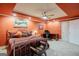 A bedroom featuring orange walls, a metal bed frame, wooden desk and a ceiling fan with lighting at 3644 Graycliff Rd, Snellville, GA 30039
