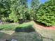 View of the backyard featuring trees, a lawn, and garden space at 6680 Bentley Trl, Cumming, GA 30040