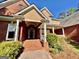 Inviting brick front porch with white columns and lush landscaping offering a warm welcome at 6680 Bentley Trl, Cumming, GA 30040