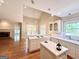 Open kitchen layout with island, white cabinets, and a view into the living area with fireplace at 6680 Bentley Trl, Cumming, GA 30040