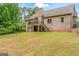 View of the backyard of a brick home with a deck, a garage, and a spacious lawn at 1233 Butler Bridge Rd, Mcdonough, GA 30252