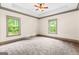A carpeted bedroom has a trey ceiling, a ceiling fan, and windows to provide ample natural light at 1233 Butler Bridge Rd, Mcdonough, GA 30252