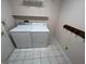 This laundry room includes a washer, dryer, tile flooring, and storage shelves at 1329 Springwood Nw Dr, Conyers, GA 30012