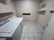 This laundry room includes a washer, dryer, tile flooring, and storage shelves at 1329 Springwood Nw Dr, Conyers, GA 30012