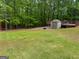 Expansive backyard with lush green lawn, mature trees, and shed with adjacent deck, perfect for outdoor activities at 712 Honeysuckle Ln, Temple, GA 30179