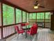 Relaxing screened porch featuring a ceiling fan and a dining table set amongst the verdant scenery at 712 Honeysuckle Ln, Temple, GA 30179