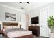Modern bedroom with sleek furnishings, including a rustic wood headboard, a large tv, and indoor plants at 368 Ginger Cake Rd, Fayetteville, GA 30214