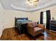 Bedroom featuring hardwood floors, dark wood furniture, and a tray ceiling with fan at 105 Meadow Spring'S Ct, Locust Grove, GA 30248
