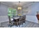 Cozy dining room features modern chandelier, a wooden dining table with six chairs, and large window at 702 Brambling Way, Stockbridge, GA 30281