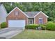 Charming brick home with a two-car garage, manicured lawn, and an ADT security system sign in the yard at 702 Brambling Way, Stockbridge, GA 30281