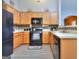 Well-lit kitchen features wood cabinets, mosaic tile backsplash, modern appliances, and gray flooring at 702 Brambling Way, Stockbridge, GA 30281