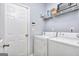 Functional laundry room with washer, dryer, and shelving for storage at 702 Brambling Way, Stockbridge, GA 30281