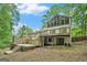 Backyard with wooden deck, stairs, and patio area surrounded by trees at 1213 Laurel Cliff Se Dr, Smyrna, GA 30082