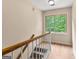 View of upper stairs with wooden railing with white spindles leading to a window overlooking greenery at 155 Grandview Trce, Fayetteville, GA 30215
