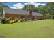 Spacious backyard featuring a brick house, lush lawn, and mature trees under a blue sky at 109 Old Virginia Cir, Jonesboro, GA 30236