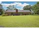 Brick home with a spacious backyard, featuring a large lawn and mature trees under a blue sky with clouds at 109 Old Virginia Cir, Jonesboro, GA 30236