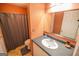 Bathroom boasts orange walls, vanity with black countertop, sink, toilet, and shower with gray curtain at 105 Kellens Ct, Fayetteville, GA 30215